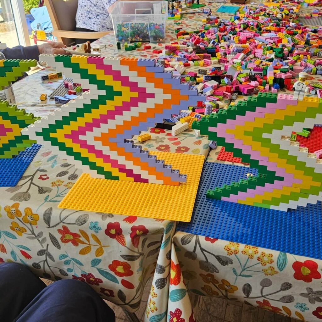 LEGO brick wall built in a zig-zag pattern using alternating colours, placed on baseplates on a table.