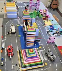 Large LEGO city layout with multicolour towers, roads, vehicles, and small figures arranged on baseplates.