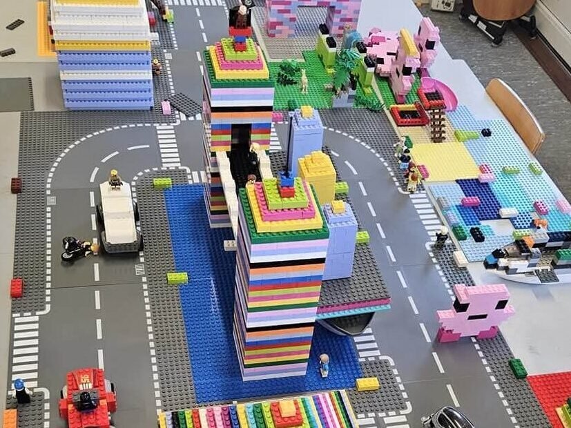 Services Large LEGO city layout with multicolour towers, roads, vehicles, and small figures arranged on baseplates.